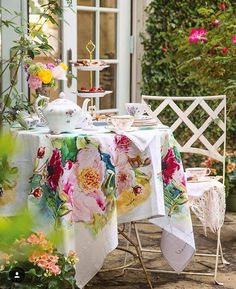 a table covered with flowers in front of a house