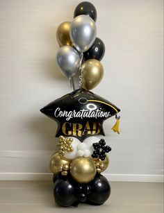 graduation balloon bouquet with congratulations graduates cap and tassels on top, black and gold balloons