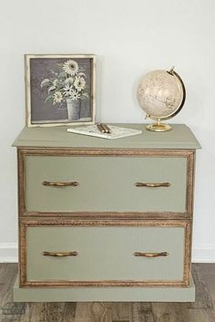 an antique dresser with two drawers and a globe on top, in front of a white wall