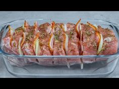 meat in a casserole dish with onions and seasoning on the top, ready to be cooked