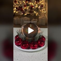 a white plate topped with red ornaments on top of a table next to a christmas tree