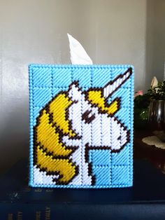 a blue and white square with a unicorn on it's face is sitting on top of a bookshelf