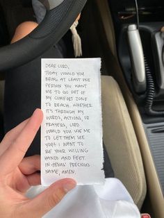 a hand holding a piece of paper with writing on it in the back seat of a car