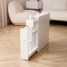 a small white cabinet sitting on top of a hard wood floor next to a chair