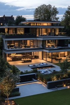 an aerial view of a modern house at night with lights on the windows and lawn area