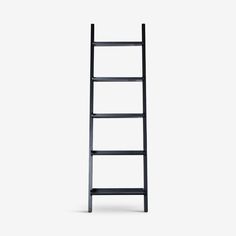 a black ladder leaning against a white wall