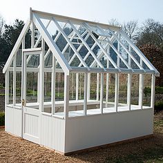 a small white greenhouse sitting in the middle of a field