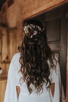 the back of a woman's head wearing a white dress with flowers in her hair