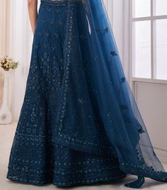 COLOR : Teal Blue FABRIC : Top (Blouse) - Soft Net, Bottom (Lehenga) - Soft Net, Dupatta - Soft Net WORK : Dori, Zarkan, Sequins OCCASION : Wedding, Reception, Mehendi, Engagement READY-TO-WEAR : NoSTITCHING : Available as semi-stitched fabric, can be stitched using standard size option (+$30). Note: There might be a slight color variation due to lighting and flash used during photoshoot. The bright shade seen is the best closer view of fabric's color. Blue Gown With Dori Work For Wedding, Blue Gown With Zari Work For Reception, Blue Gown With Dori Work For Reception, Blue Gown With Customizable Fit For Reception, Blue Designer Dress With Sheer Dupatta, Blue Gown With Dori Work In Traditional Drape, Blue Gown With Dori Work And Traditional Drape, Blue Gown With Resham Embroidery And Traditional Drape, Blue Lehenga With Sheer Dupatta For Eid