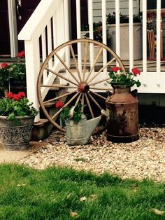 an old wagon wheel and flower pots on the side of a house