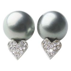 A pair of Tahitian black pearl and diamond earrings, with a pair of Tahitian black pearls, measuring approximately 12.9mm and 13.5mm respectively, each with a heart below, pavé set, round brilliant-cut diamonds, mounted in 14ct white gold, with posts and butterfly backs, circa 1990. Tahitian Pearl Earrings, Sapphire And Diamond Earrings, Vintage Stud Earrings, Diamond Cluster Earrings, Pearl And Diamond Earrings, White Gold Earrings, Tahitian Pearls, Antique Earrings, Pretty Earrings