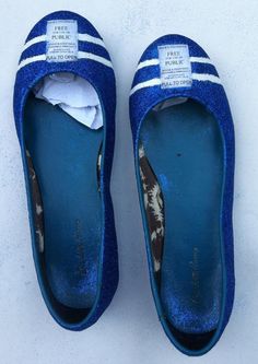 blue slippers with white stripes on the bottom and one shoe in the middle, sitting on