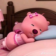 a pink teddy bear laying on top of a bed