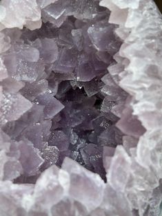 the inside of a purple and white rock with lots of small crystals in it's center