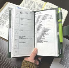 a person holding an open book on top of a desk