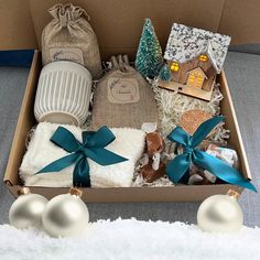 a box filled with christmas items on top of a white blanket and blue ribbon wrapped around it