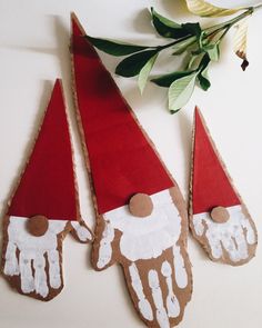 three red and white gnome hats sitting on top of a table next to a flower