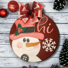 a wooden plaque with a snowman on it next to christmas decorations and pine cones