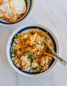 two bowls filled with rice and vegetables on top of a white countertop next to each other