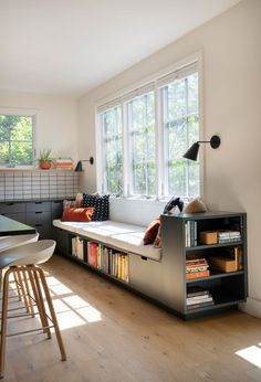 a living room filled with furniture and a book shelf next to a window on top of a hard wood floor