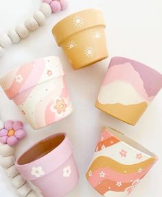 four flower pots sitting next to each other on top of a white table with beads