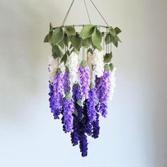 purple and white flowers are hanging from a metal wire with green leaves on it in a room