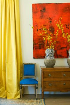 two vases with yellow flowers are sitting on a dresser in front of a painting