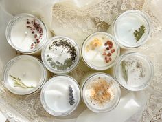 six jars filled with different types of herbs on a lace doily covered tablecloth