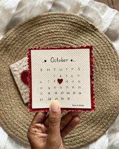 someone is holding up a calendar card with the word october on it and a red heart