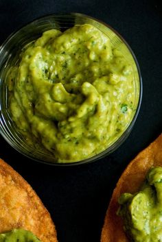 a bowl of guacamole next to two pieces of bread