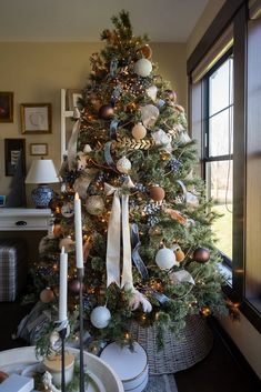 a decorated christmas tree in a living room with candles and plates on the table next to it