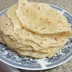 a stack of tortillas sitting on top of a blue and white plate