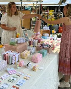 two women standing next to each other in front of a table with gifts on it