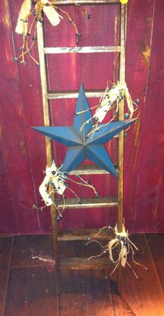 a wooden ladder with a blue star hanging from it's side on a wood floor