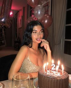 a woman sitting in front of a cake with candles on it