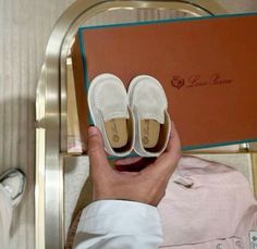 a person holding up two pairs of white shoes in front of a red box with the word love written on it