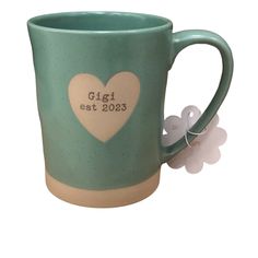 a ceramic mug with a heart on the side and a tag attached to it that says gigi est 2003