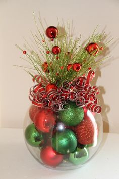 a glass vase filled with ornaments and greenery