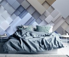 a bed with blue sheets and pillows in front of an artistic wallpaper design that looks like hexagonal blocks