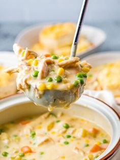 a ladle full of chicken pot pie soup with peas and corn on the side