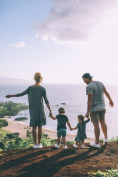 a family standing on top of a hill next to the ocean