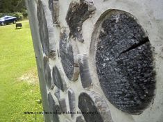 a stone wall with holes in the middle and grass on both sides next to it