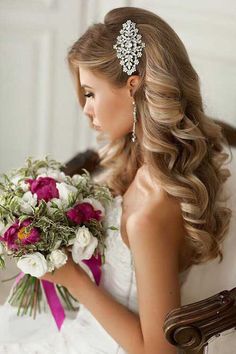 a woman in a wedding dress holding a bouquet and wearing a bridal hair comb