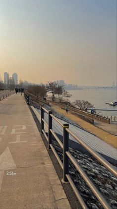 an image of a city street with people walking on the sidewalk and water in the background