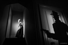 a woman in a long dress and hat standing on the stairs next to a door