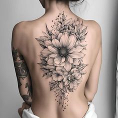 the back of a woman's body with flowers tattooed on her upper and lower back