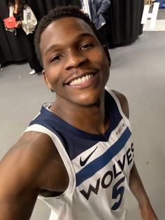 a man in a basketball uniform smiling for the camera