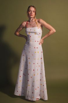 The designer Estefanía Álvarez's mastery in balancing modern shapes with romantic femininity is evident in the Rainbow Cherry Tomato dress. Crafted with lightweight and lustrous linen, this elegant and cheerful dress is detailed with an embroidery of flowers and cherry tomatoes, adorned with a delicate multicolored bias ribbon that enhances the back. Pair it with a simple pair of low-heeled sandals and an open back for a bold yet sophisticated look. Fitted Linen Dress With Floral Print, Fitted Floral Embellished Maxi Dress For Summer, Spring Dress With Floral Embroidery And Fitted Bodice, Fitted Floral Print Linen Midi Dress, Fitted Linen Midi Dress With Floral Print, Fitted Floral Print Linen Dress For Garden Party, Fitted Linen Dress With Floral Print For Garden Party, Fitted Linen Floral Dress For Garden Party, Fitted Floral Maxi Dress For Garden Party