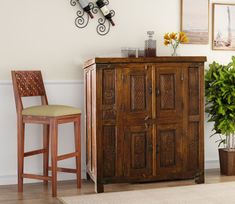 a wooden cabinet sitting next to a chair and potted plant on top of a hard wood floor