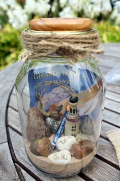 a jar filled with sand and rocks on top of a wooden table